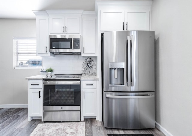kitchen with white cabinets, wood finished floors, appliances with stainless steel finishes, and decorative backsplash