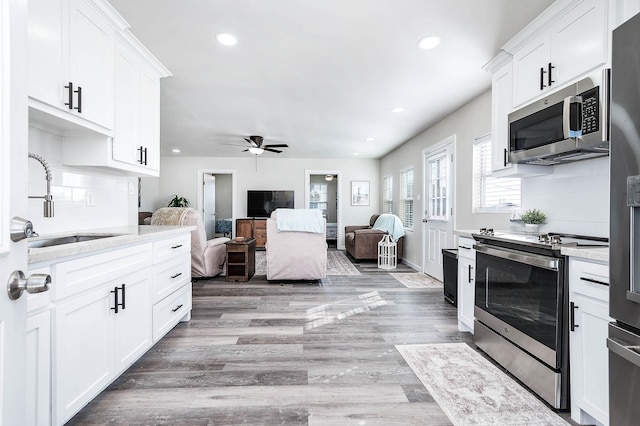 kitchen featuring light countertops, ceiling fan, stainless steel appliances, tasteful backsplash, and a sink