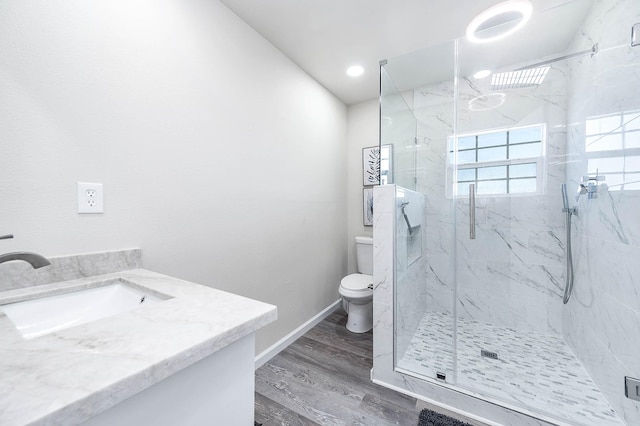 bathroom with vanity, a marble finish shower, toilet, baseboards, and wood finished floors