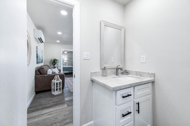 bathroom with a wall mounted AC, vanity, wood finished floors, ensuite bathroom, and baseboards