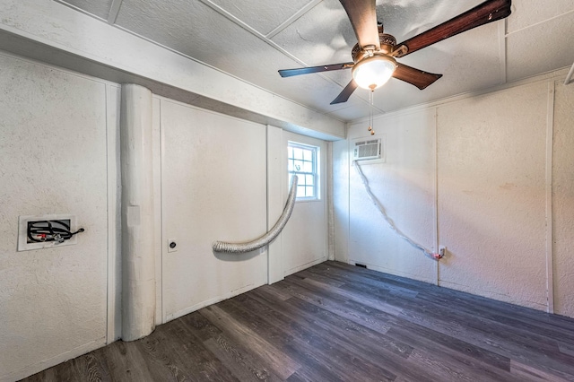 unfurnished bedroom with a wall mounted air conditioner, ceiling fan, wood finished floors, and a textured wall