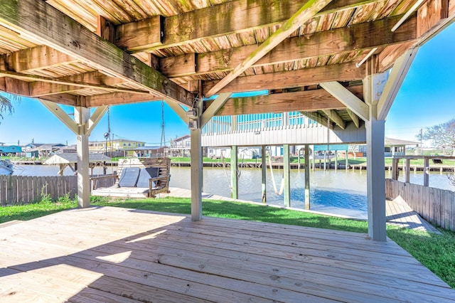 deck featuring a water view, fence, and a boat dock