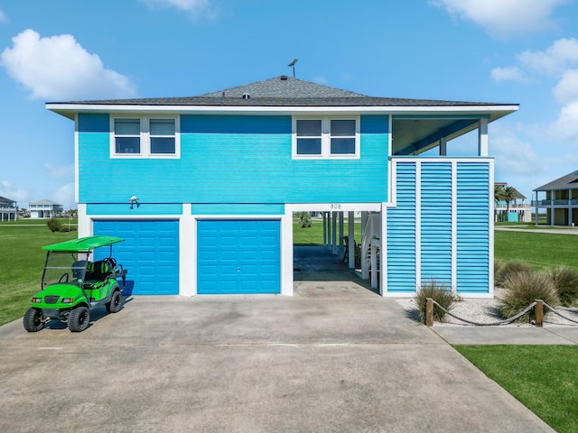 raised beach house with a front yard, driveway, a garage, and a carport