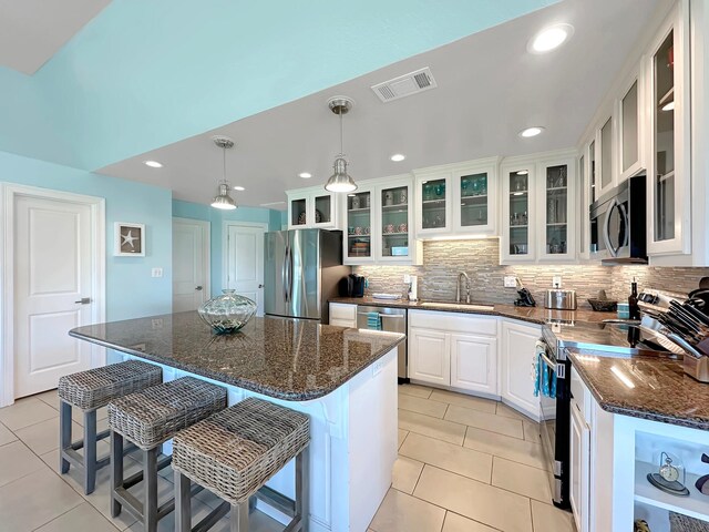 kitchen with a sink, stainless steel appliances, light tile patterned floors, visible vents, and white cabinets