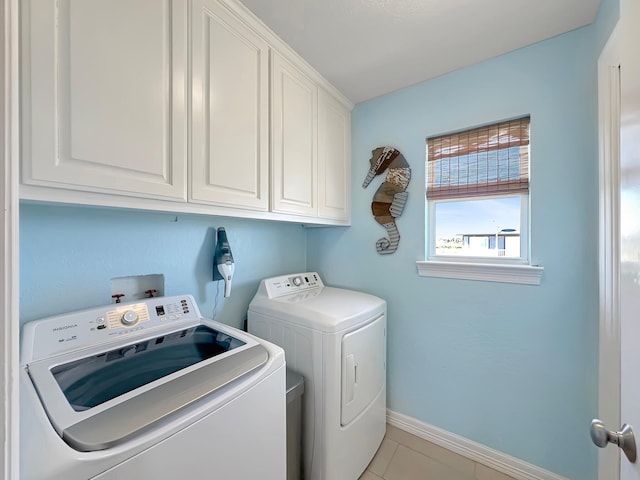 laundry area featuring baseboards, cabinet space, light tile patterned flooring, and washer and clothes dryer