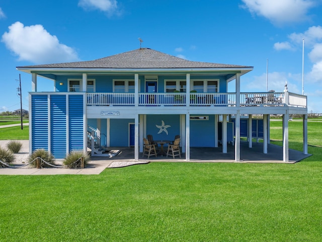 back of house with a patio, a shingled roof, and a lawn