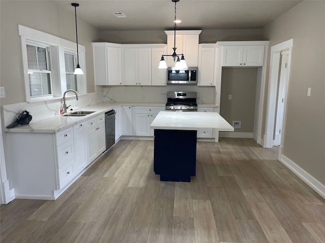 kitchen with a sink, a center island, appliances with stainless steel finishes, and light wood finished floors