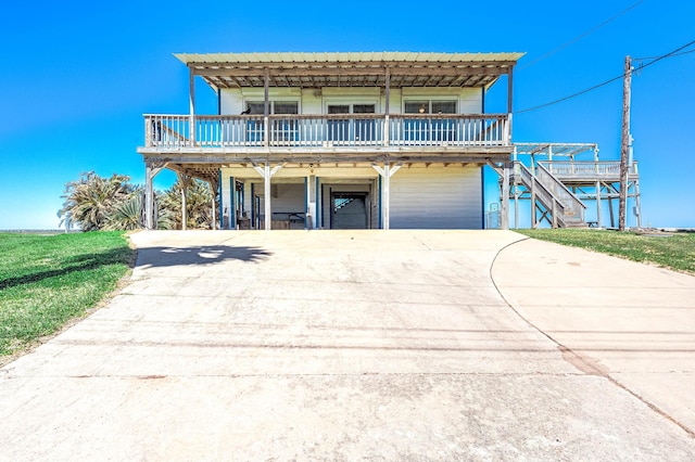 view of front facade with concrete driveway, a wooden deck, and stairway