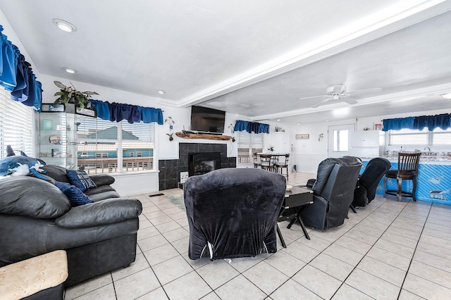 living area with beam ceiling, ceiling fan, light tile patterned flooring, and a fireplace