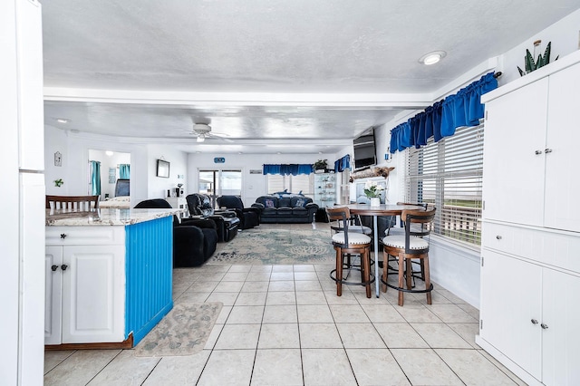 interior space featuring light tile patterned floors, a ceiling fan, and a textured ceiling