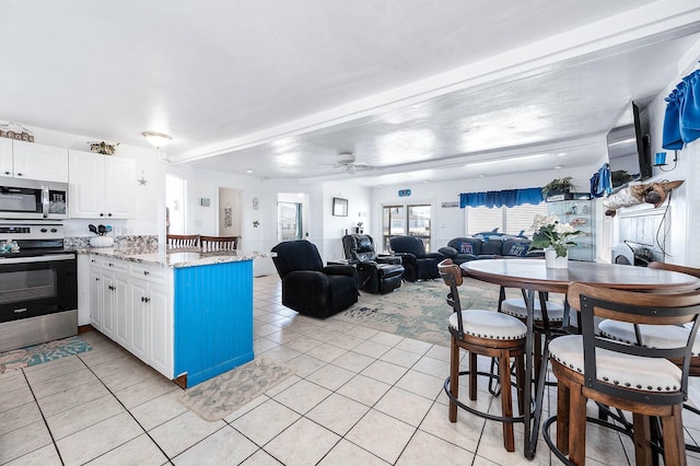 kitchen featuring light tile patterned floors, ceiling fan, a peninsula, white cabinetry, and appliances with stainless steel finishes