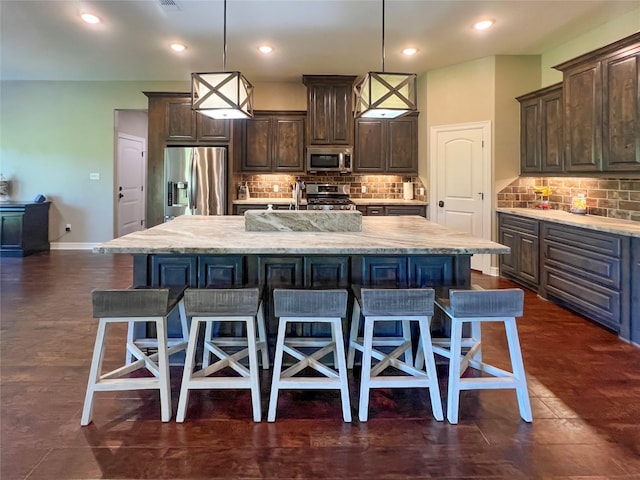 kitchen featuring dark brown cabinets, a kitchen breakfast bar, a large island with sink, and stainless steel appliances