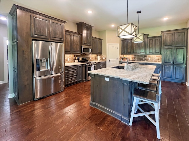kitchen with dark wood-style floors, backsplash, dark brown cabinets, stainless steel appliances, and a sink