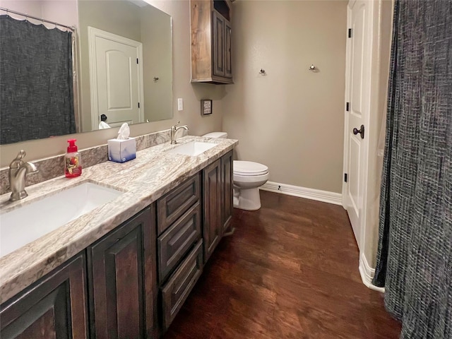 bathroom with toilet, wood finished floors, a sink, and baseboards
