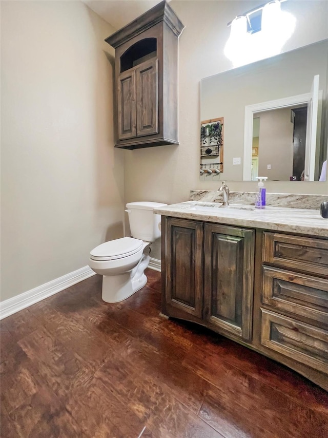 bathroom with vanity, baseboards, toilet, and wood finished floors