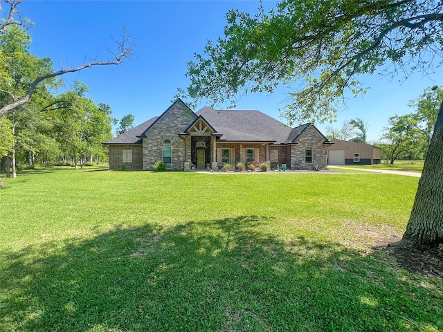 craftsman house featuring a front yard, roof with shingles, stone siding, and a detached garage