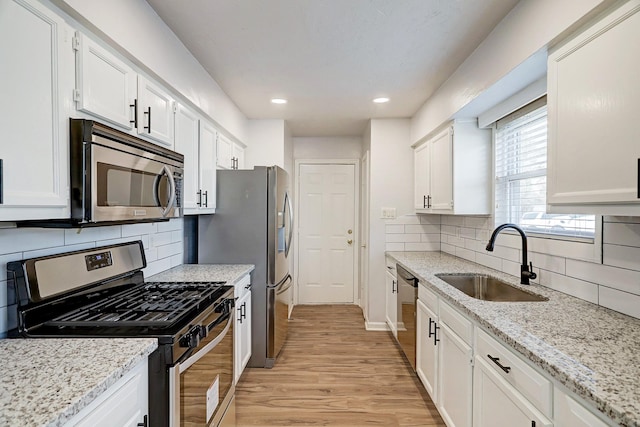 6802 Prairie Village Dr, Katy, TX 77449 - kitchen with white cabinetry, light wood-type flooring, a sink, light stone counters, and appliances with stainless steel finishes