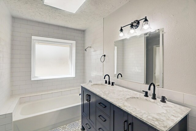6802 Prairie Village Dr, Katy, TX 77449 - bathroom featuring a washtub, double vanity, a sink, and a textured ceiling