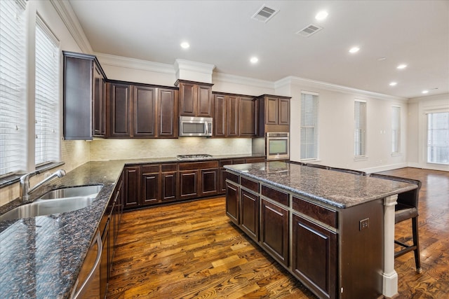 kitchen featuring visible vents, a sink, a center island, and stainless steel appliances
