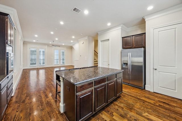 kitchen with dark wood-style flooring, dark brown cabinetry, a kitchen island, stainless steel refrigerator with ice dispenser, and ornamental molding