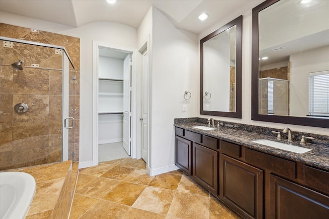 full bathroom with double vanity, a sink, a spacious closet, and a shower stall