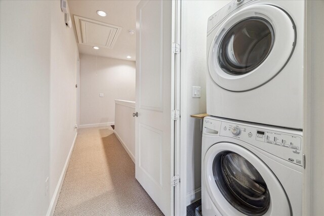 washroom with stacked washer and dryer, laundry area, light carpet, attic access, and baseboards