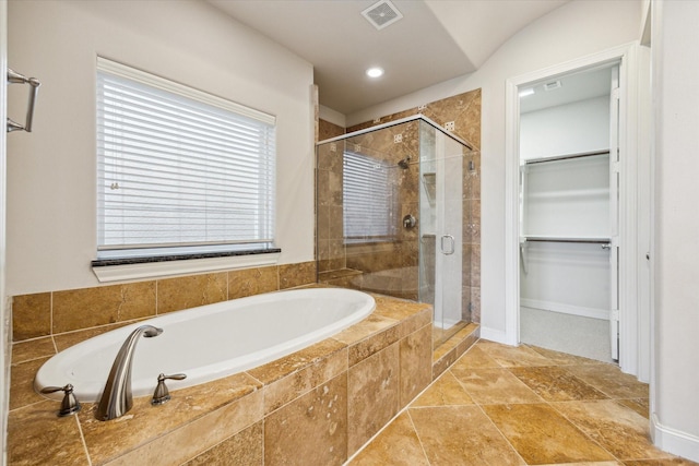 full bathroom with a walk in closet, a stall shower, a bath, and visible vents