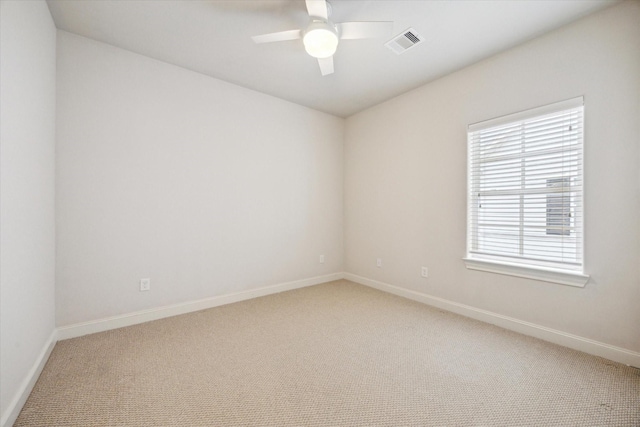 spare room with baseboards, ceiling fan, light carpet, and visible vents