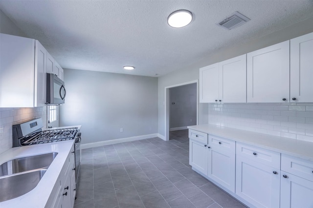 kitchen featuring white cabinets, visible vents, tasteful backsplash, a textured ceiling, and appliances with stainless steel finishes