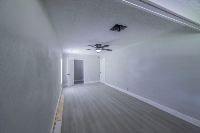 empty room with dark wood finished floors, a textured ceiling, a ceiling fan, and baseboards