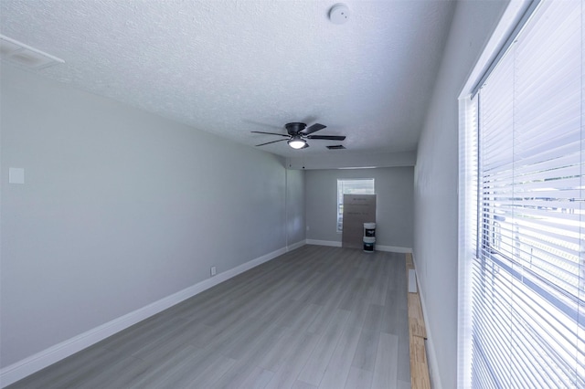 empty room featuring ceiling fan, visible vents, light wood-style floors, and a textured ceiling