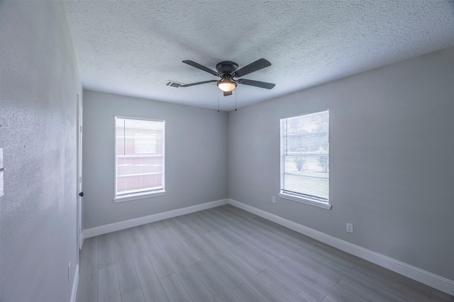 unfurnished room with ceiling fan, baseboards, wood finished floors, and visible vents