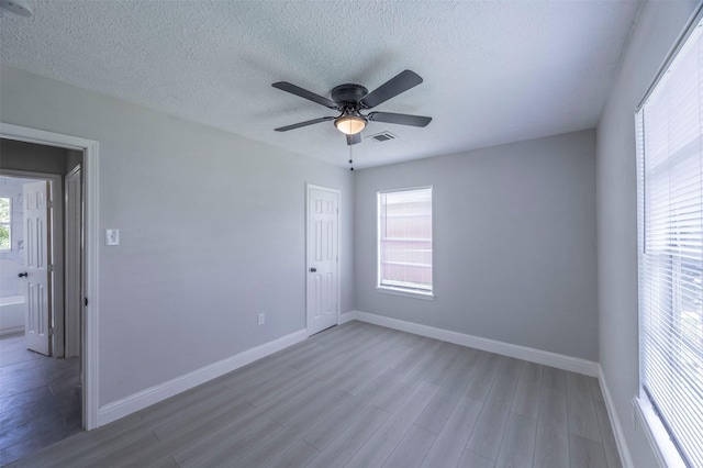 unfurnished room featuring visible vents, plenty of natural light, baseboards, and wood finished floors