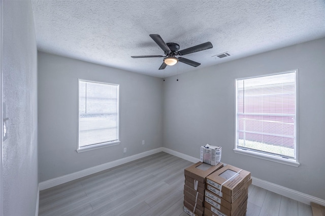 spare room featuring wood finished floors, a healthy amount of sunlight, baseboards, and ceiling fan