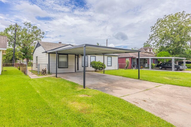 view of front of house featuring driveway, a front yard, fence, and an attached carport