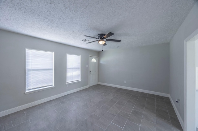 tiled spare room featuring baseboards, visible vents, a textured ceiling, and ceiling fan