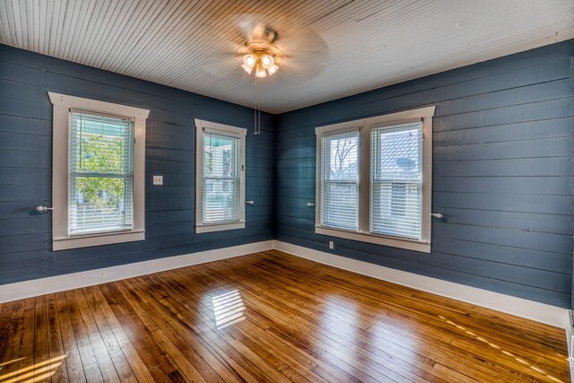 607 Center St, Brenham, TX 77833 - unfurnished room with hardwood / wood-style floors, wood walls, a ceiling fan, and baseboards