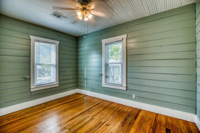 607 Center St, Brenham, TX 77833 - spare room featuring a ceiling fan, visible vents, wood walls, baseboards, and hardwood / wood-style floors