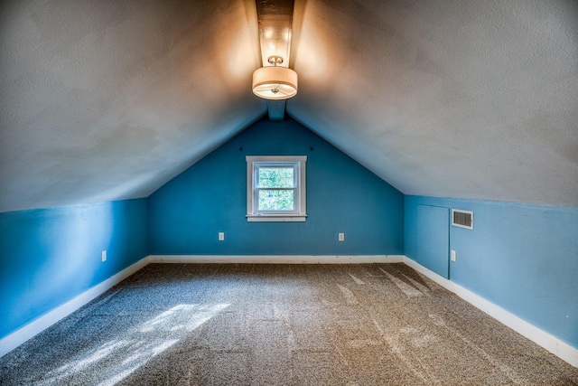 607 Center St, Brenham, TX 77833 - additional living space featuring lofted ceiling, a textured ceiling, visible vents, baseboards, and carpet