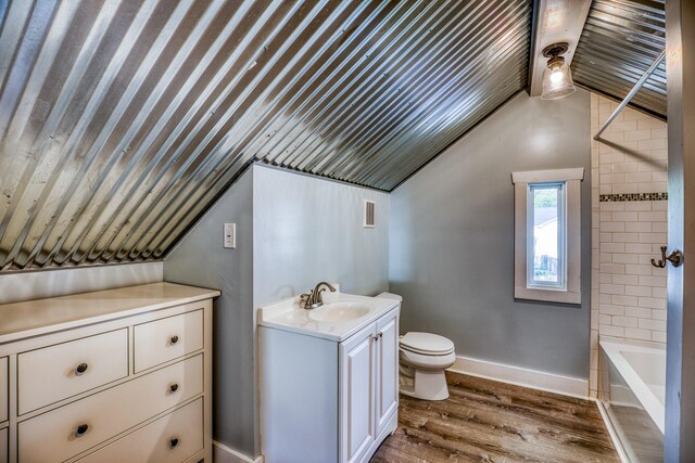 607 Center St, Brenham, TX 77833 - full bath featuring wood finished floors, toilet, lofted ceiling, and vanity