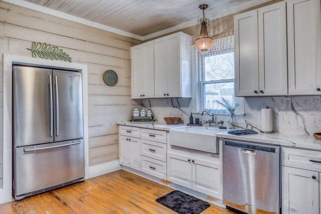 607 Center St, Brenham, TX 77833 - kitchen featuring light stone countertops, a sink, stainless steel appliances, light wood-style floors, and white cabinetry
