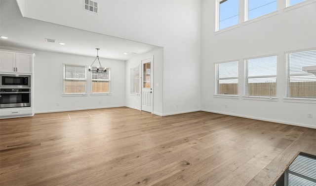 924 Wormwood Dr, League City, TX 77573 - unfurnished living room with a chandelier, light wood-style floors, recessed lighting, and a high ceiling