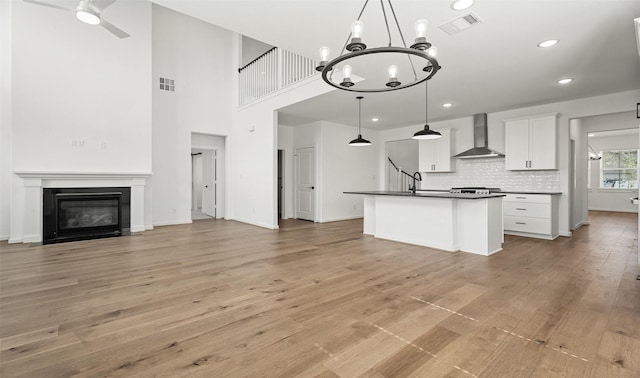 924 Wormwood Dr, League City, TX 77573 - kitchen with wall chimney exhaust hood, dark countertops, white cabinetry, a chandelier, and light wood-style flooring
