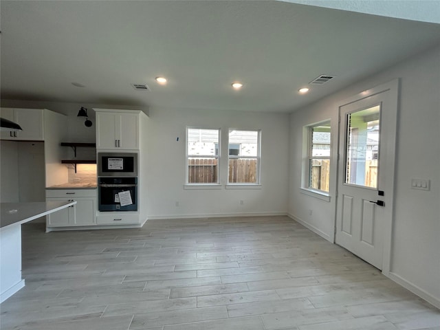 924 Wormwood Dr, League City, TX 77573 - kitchen with light wood-style flooring, white cabinets, recessed lighting, built in microwave, and light countertops