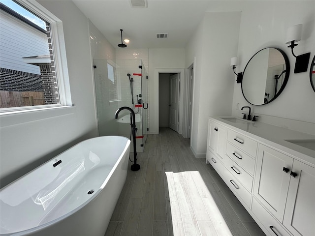 924 Wormwood Dr, League City, TX 77573 - bathroom featuring a stall shower, a freestanding bath, double vanity, and wood finished floors