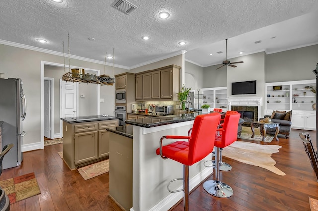 108 Somerton Dr, Montgomery, TX 77356 - kitchen with appliances with stainless steel finishes, a center island, ornamental molding, a ceiling fan, and dark wood finished floors