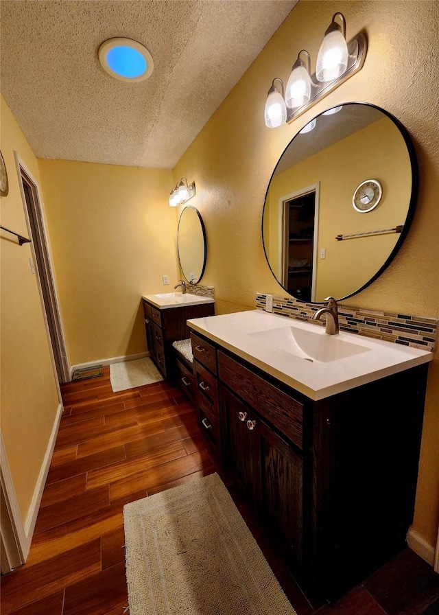 8300 Fm 1459th Rd, Sweeny, TX 77480 - bathroom featuring two vanities, a textured ceiling, wood finished floors, and baseboards