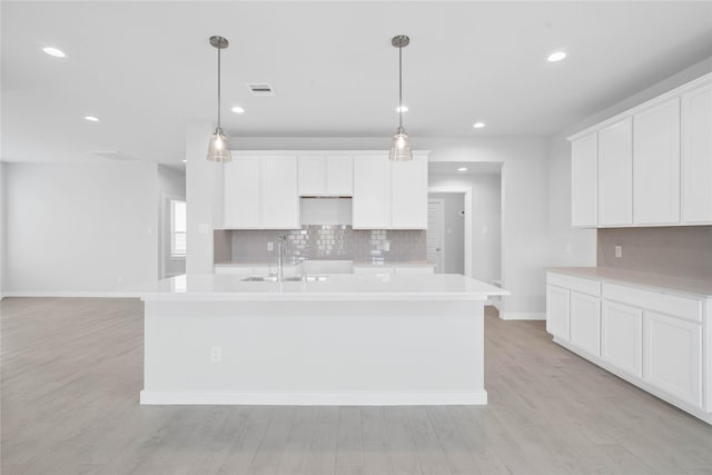 365 Spruce Oak Ln, Waller, TX 77484 - kitchen featuring a sink, backsplash, baseboards, an island with sink, and light wood-style flooring