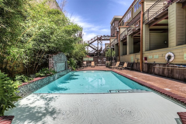 view of pool with fence, a fenced in pool, stairway, and a patio area