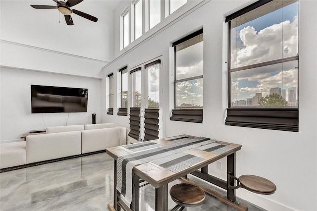 dining area with a towering ceiling and ceiling fan